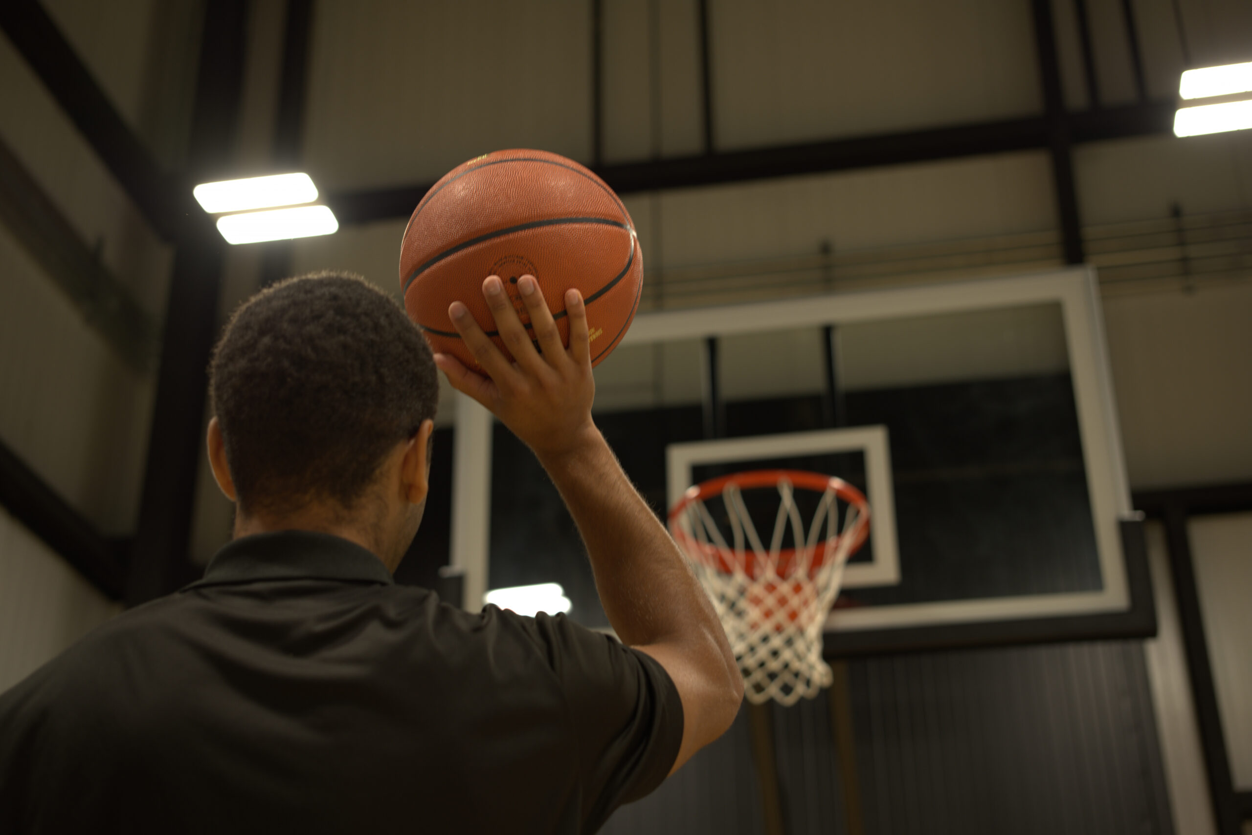 Athelet holding a basketball, aiming it at a basketball net